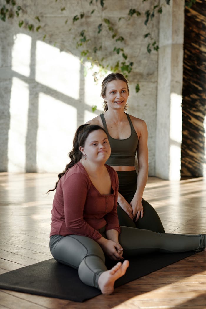 Two women practice yoga together, emphasizing inclusivity and healthy lifestyle indoors.